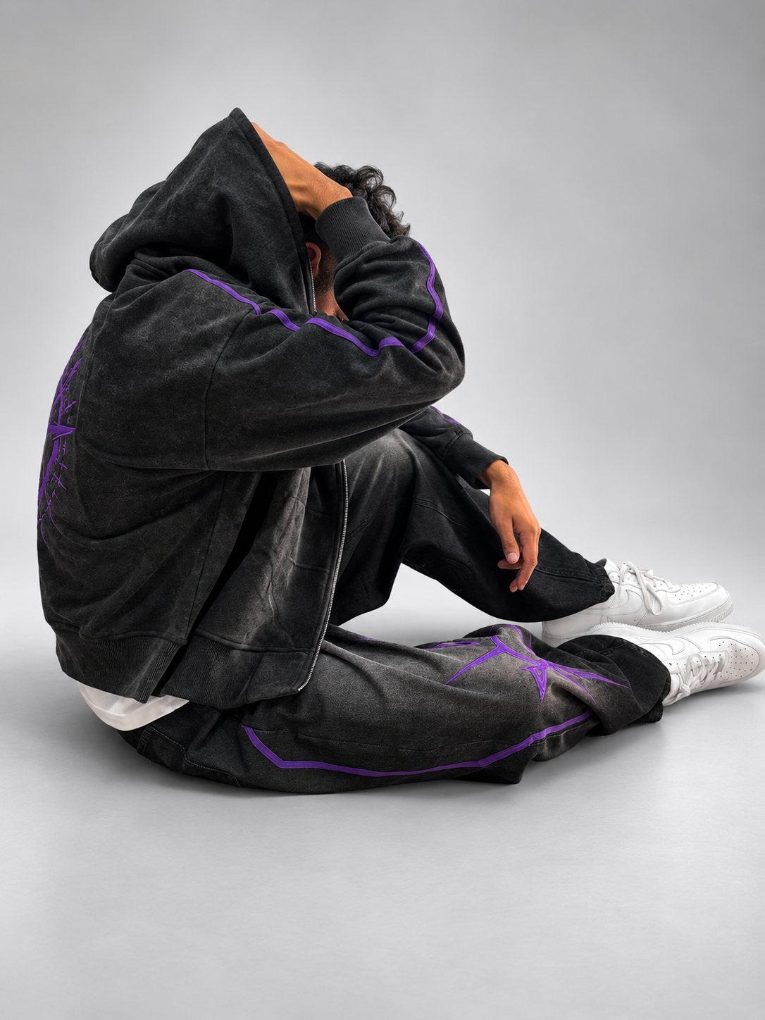 Model seated with hood up in the Drop 001 hoodie and jeans
